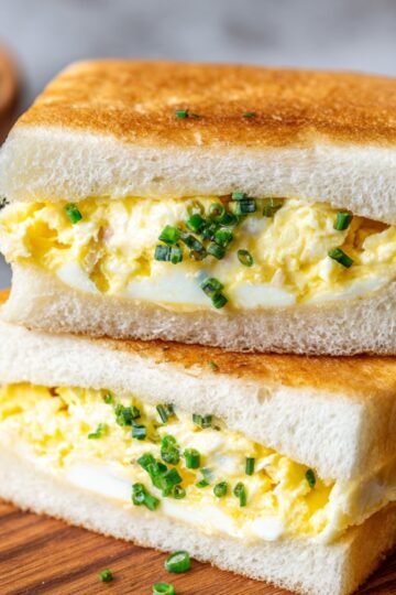 A soft Japanese Egg Sandwich filled with scrambled eggs, showcasing a fluffy, creamy texture between slices of white bread.
